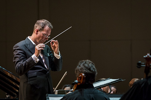 A director directs the orchestra during a live performance